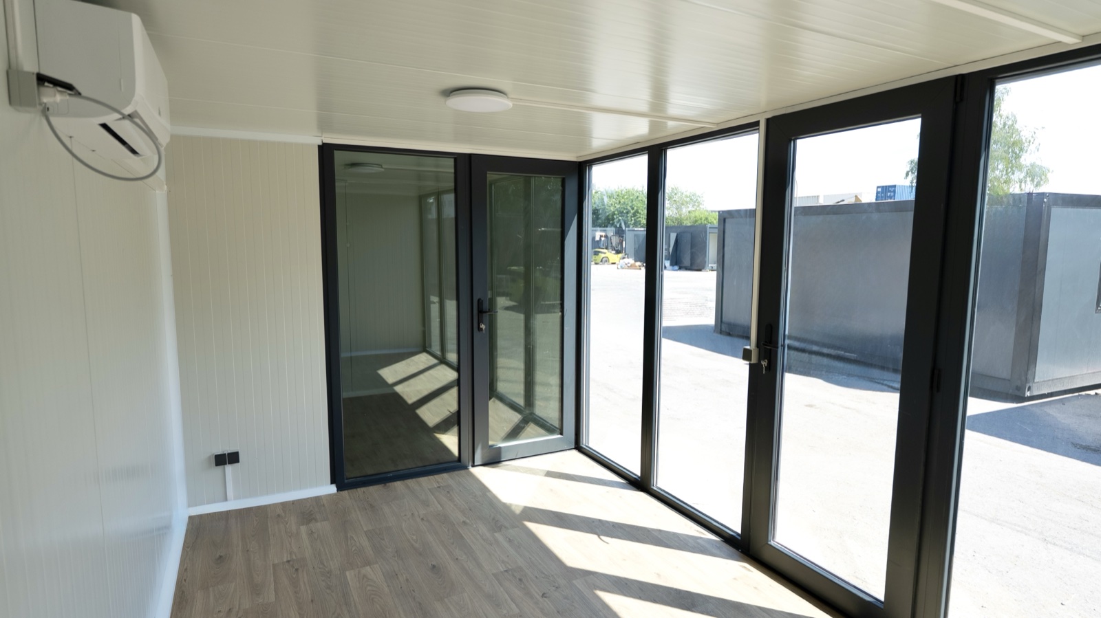 Innenraum des Wohnmoduls: heller Aufenthalt mit Holzboden und Glasfront